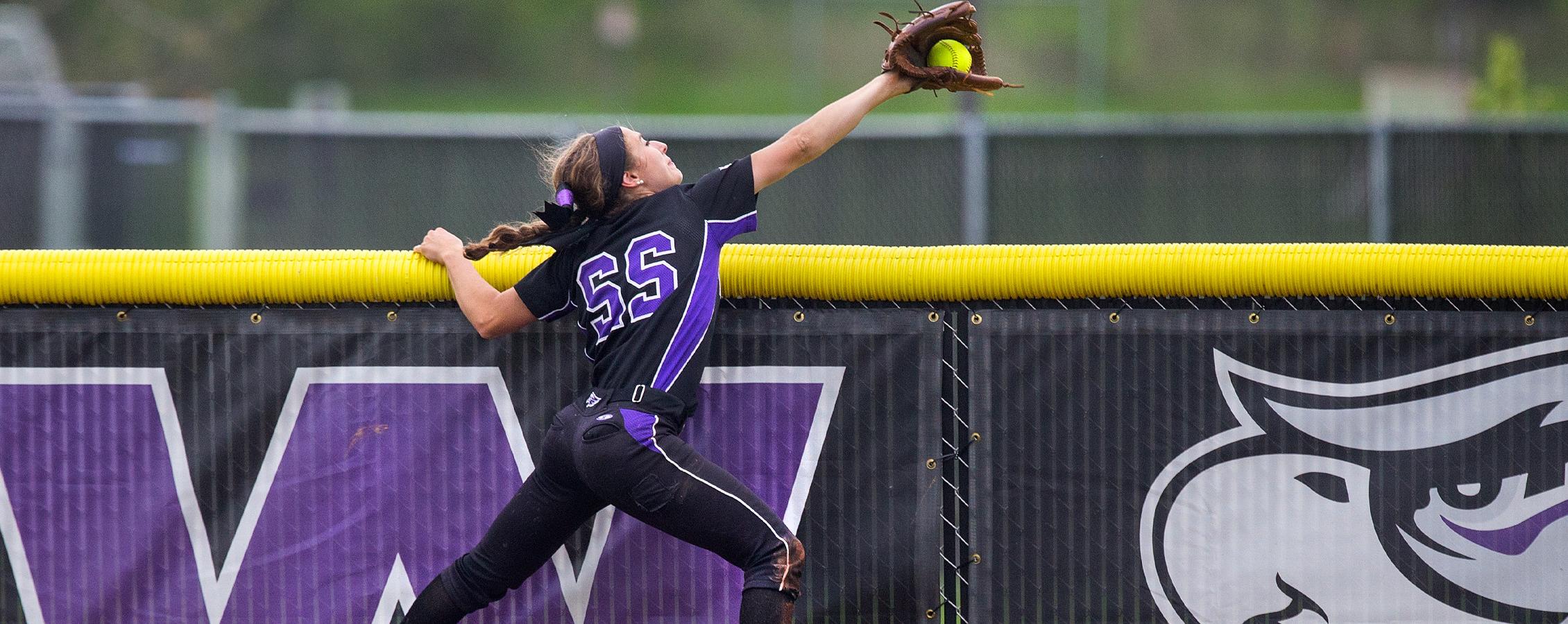 A Warhawk women's basketball player jumps through two opponents to get the basketball.