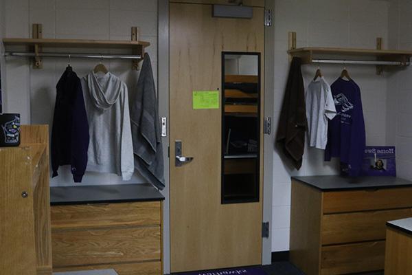 Two shelfs on the left and right sides of the door. Each shelf has a bar with clothes hanging on it, and there a dressers underneath each shelf as well.