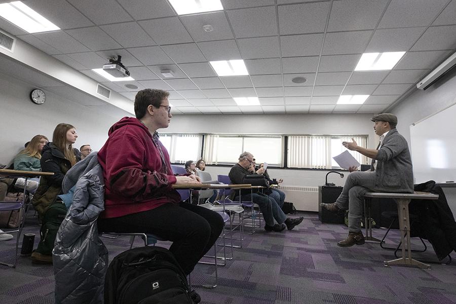 Nick Gulig sits on a table and speaks to a class.