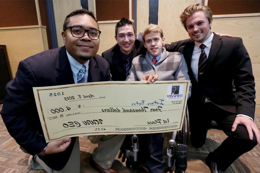 Four students hold a large check.